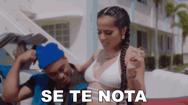 a woman in a white bikini is standing next to a man in a blue hat and the words se te nota are visible