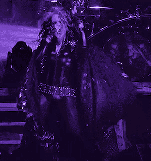 a woman singing into a microphone with a drummer in the background