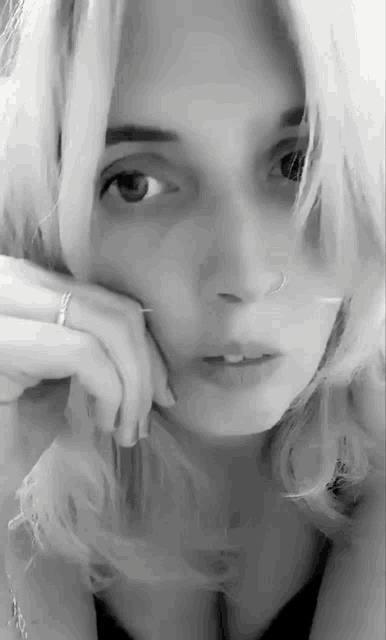 a woman with blonde hair and a nose ring looks at the camera
