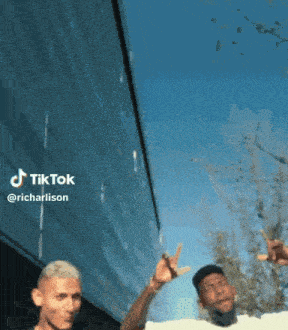 two men are standing in front of a building with a blue sky in the background and a tiktok watermark on the bottom right
