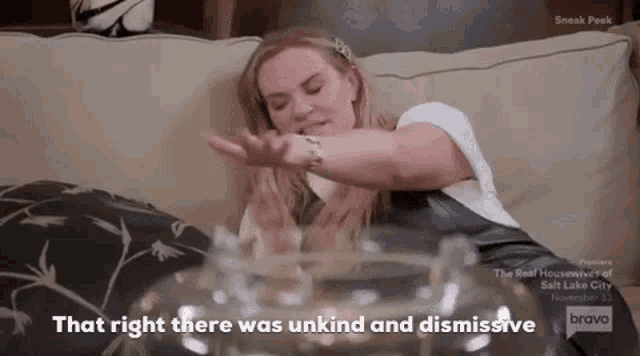 a woman is sitting on a couch with her arm outstretched and a glass in front of her .