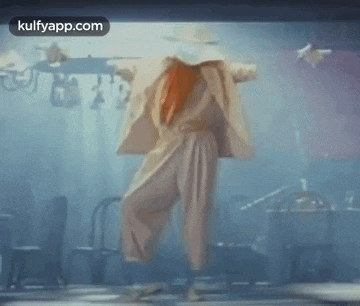 a woman with red hair is dancing in a room with a sign that says kulfyapp.com