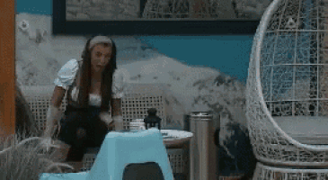 a woman is sitting on a couch next to a wicker chair