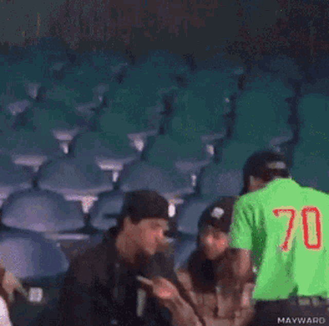 a man and a woman are sitting in a stadium watching a baseball game .