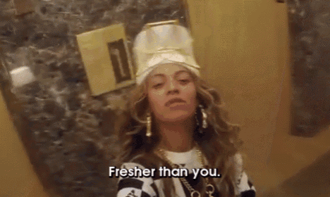 a woman wearing a chef 's hat and earrings is standing in front of a wall and says fresher than you .