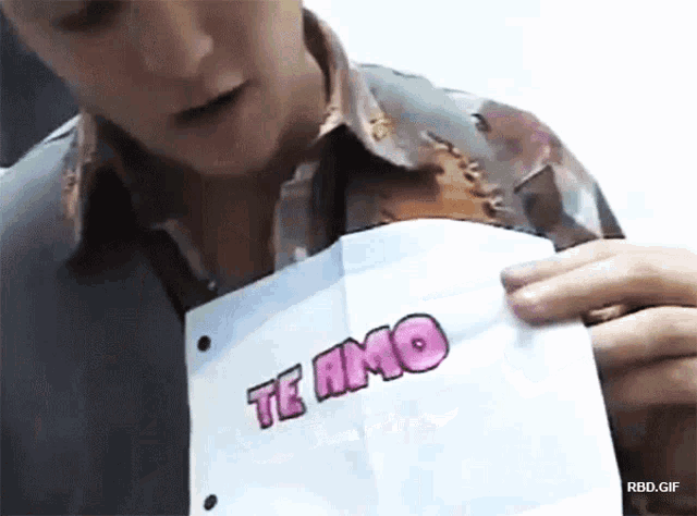 a man is holding up a piece of paper that says te amo