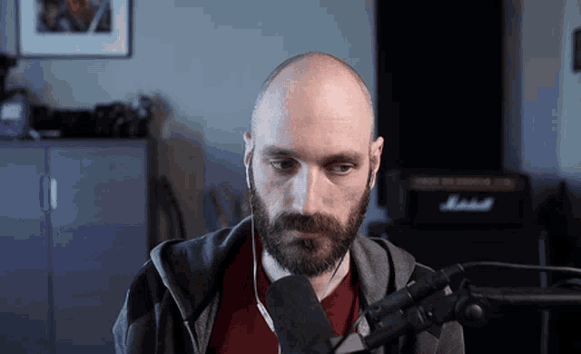 a bald man with a beard stands in front of a marshall amp