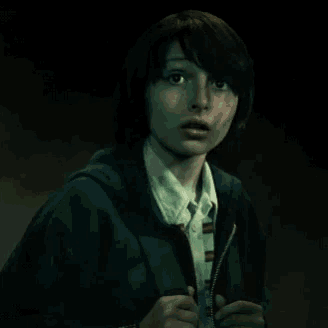 a young girl wearing a blue hoodie and a white shirt is looking at the camera with a surprised look on her face