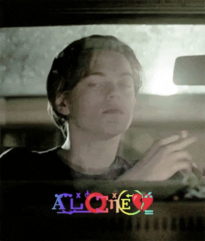 a young man is smoking a cigarette in a car with the word alone written on the window