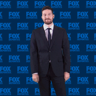 a man in a suit is standing in front of a fox deportes wall