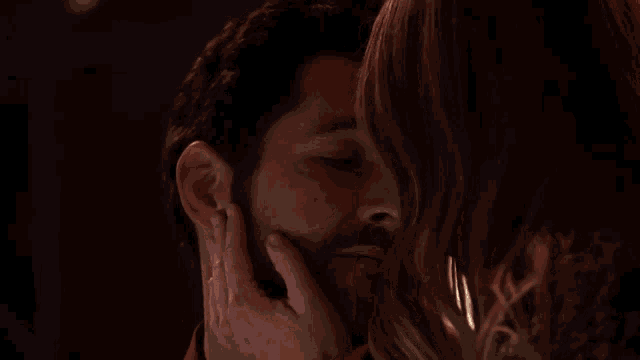 a man and a woman are kissing and the woman is touching the man 's face
