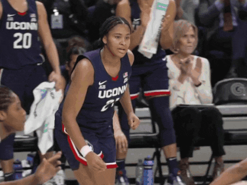 a uconn basketball player stands on the court with her teammates
