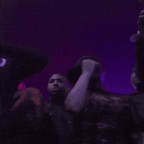 a woman is singing into a microphone on a stage in a dark room .