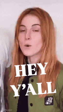 a woman with red hair is wearing a green jacket and saying hey y'all