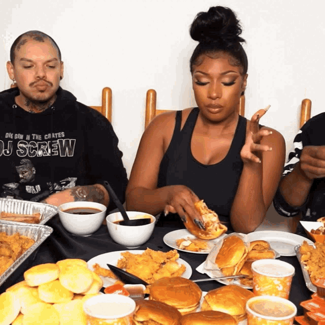 a man in a dj screw shirt sits at a table