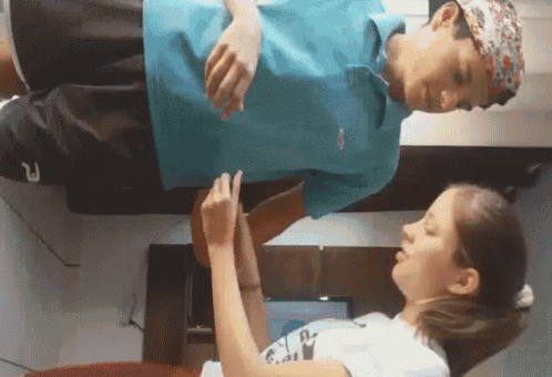a boy and a girl are playing with each other in a living room . the boy is wearing a blue polo shirt .