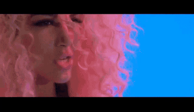 a close up of a woman 's face with a pink wig on a blue background .