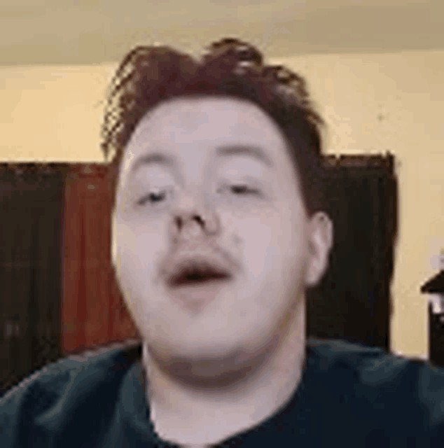 a man with a beard is making a funny face while looking at the camera .