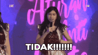a girl is holding a microphone and says tidak