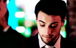 a man in a suit and tie looks down with his eyes closed