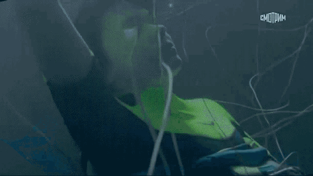 a man in a neon green wet suit is swimming in the ocean .