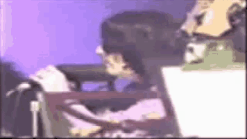 a blurry picture of a person sitting in front of a microphone and a laptop .