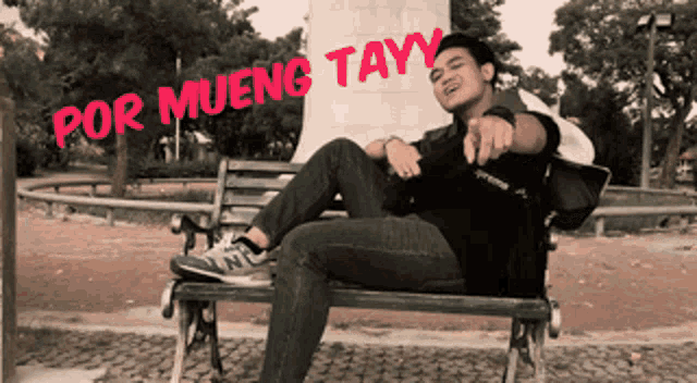 a man sits on a park bench with the words por mueng tayy written on the side