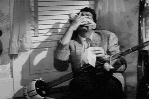 a black and white photo of a man sitting in front of a window holding a napkin and a telephone .