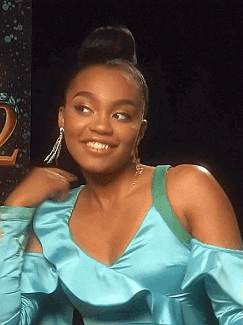 a woman wearing a blue dress and earrings smiles