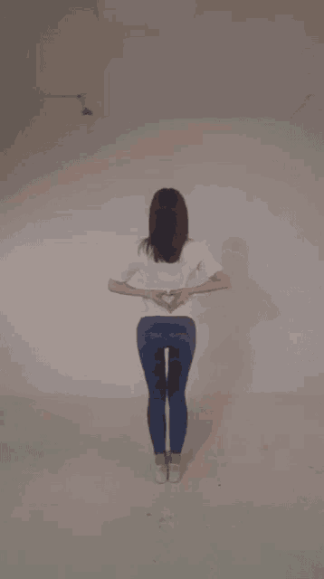 a woman making a heart shape with her hands behind her back