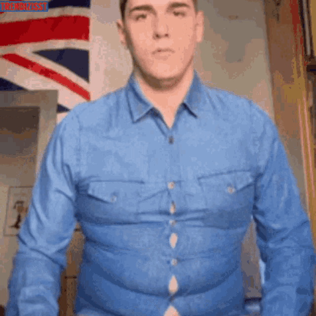 a man in a blue shirt is standing in front of an british flag