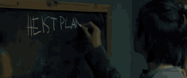 a person is writing on a blackboard that says heist plan