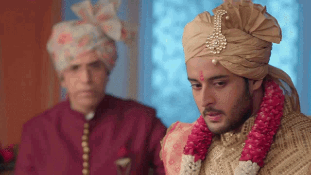 a man in a turban stands next to a man in a red shirt