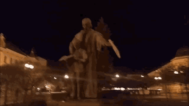 a statue of a man holding a sword is lit up in the dark