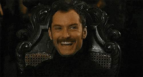 a man with a mustache is sitting in a chair with his mouth open .