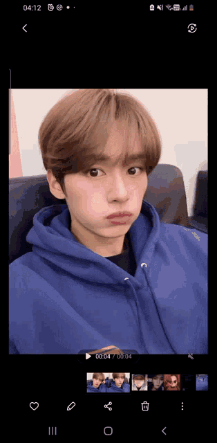 a young man wearing a blue hoodie is taking a selfie