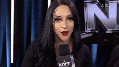 a woman with red lipstick is holding a microphone with the word nxt on it