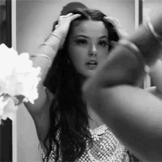 a woman is looking at herself in the mirror while a man blow dries her hair .