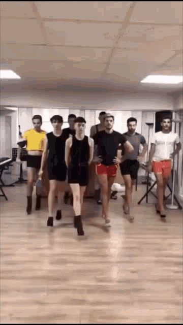 a group of men and women are dancing in a room .