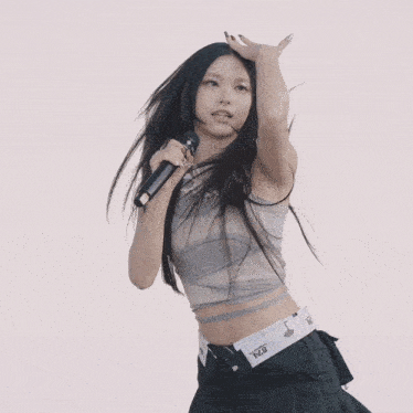 a woman singing into a microphone wearing a crop top and a black skirt with the word dickies on the waistband