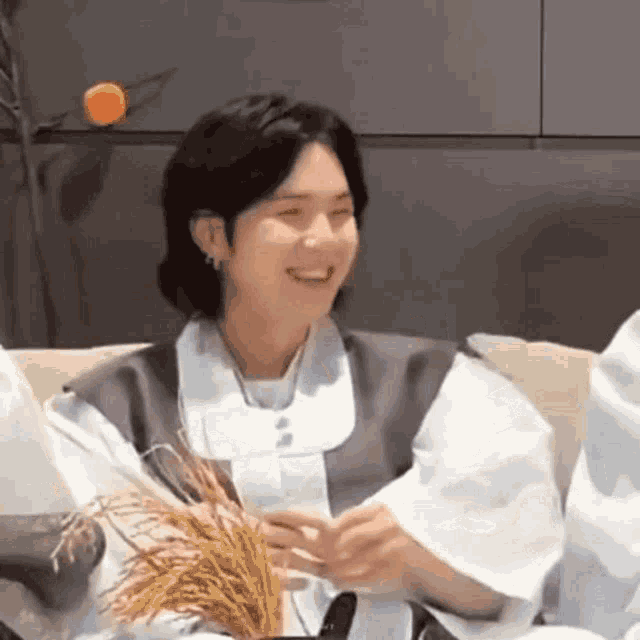 a man is sitting on a couch holding a bunch of rice .