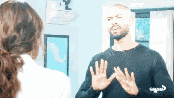 a man in a black sweater is talking to a woman who is wearing a white shirt with the word global on it