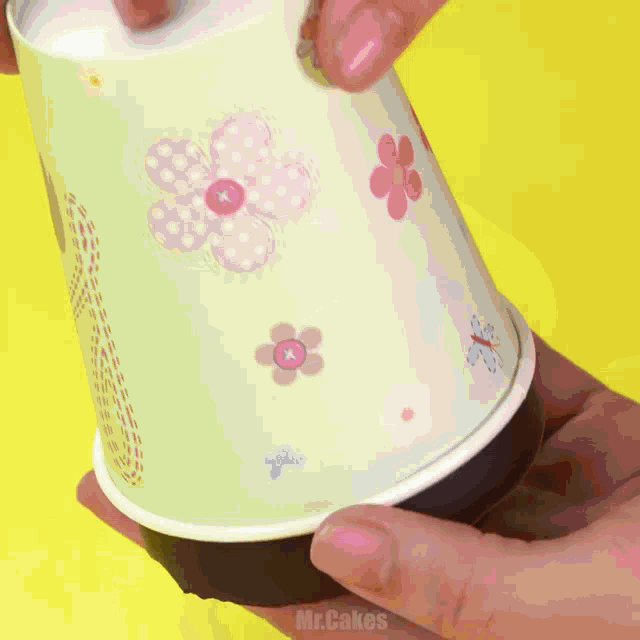 a person holding a paper cup with flowers on it