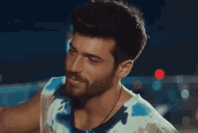 a close up of a man with a beard wearing a blue and white tank top .