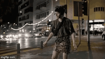 a person in a leopard print skirt is walking down a street at night