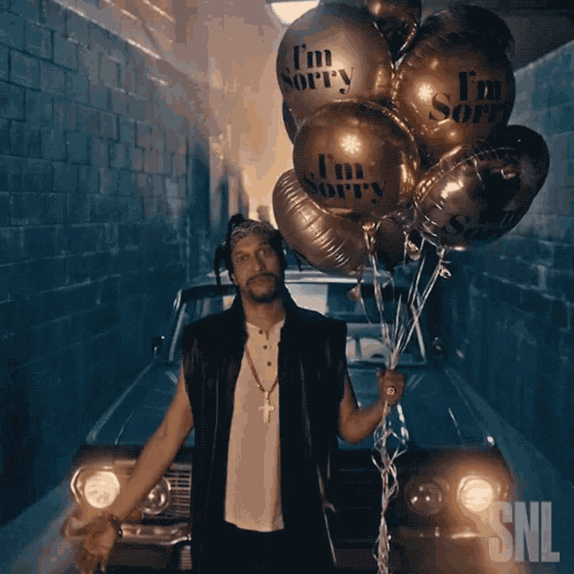a man holding a bunch of i 'm sorry balloons in front of a car