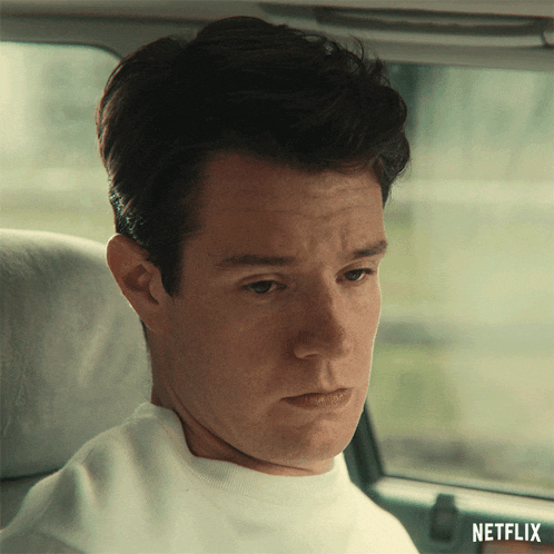 a man in a white shirt is sitting in a car with a netflix logo behind him