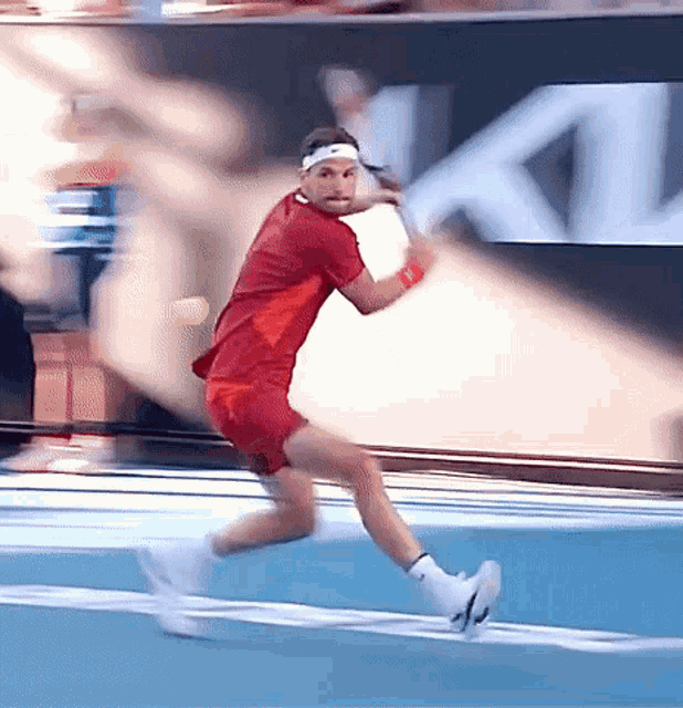 a man in a red shirt and red shorts is running with a tennis racquet