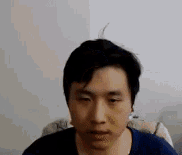 a close up of a man 's face with a blue shirt on looking at the camera .