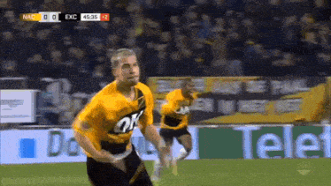 two soccer players are running on a field with a sign that says tele on it